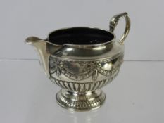 A Victorian Silver Cream Jug, embossed with ribbon and swags, London hallmark, dated 1885/6, mm John