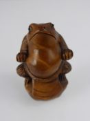 A Japanese Netsuke, in the form of a toad posing as a Tsuma wrestler, character marks to base.