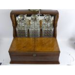 An Edwardian Oak Mirrored Back Tantalus, with three cut glass decanters, having carrying handles