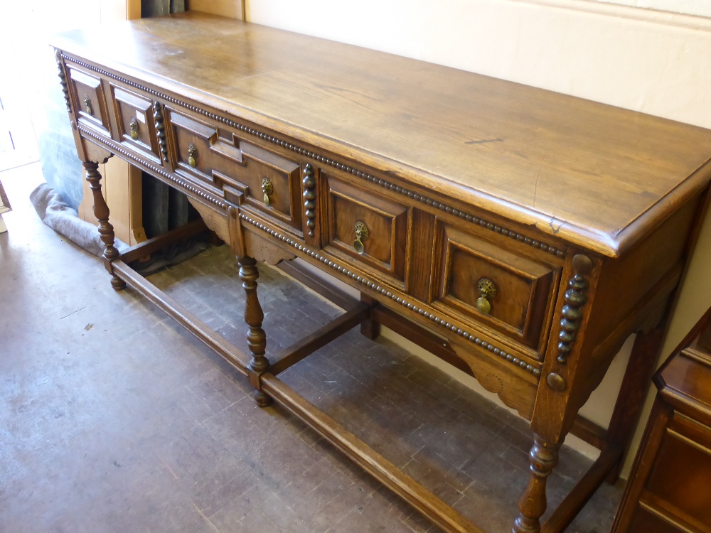 An Elizabethan Style Oak Dresser, the dresser having three drawers on turned legs with stretchers,