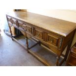 An Elizabethan Style Oak Dresser, the dresser having three drawers on turned legs with stretchers,