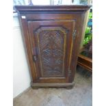 An Antique Oak Corner Cabinet, with decorative floral carving to door front, three internal