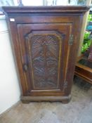 An Antique Oak Corner Cabinet, with decorative floral carving to door front, three internal