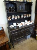 A Stained Oak Dresser, three short drawers with two cupboards beneath and two shelves with a central