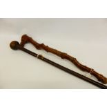 A Briar wood Walking Stick, carved with a grotesque together with a hardwood knop kierie. (2)