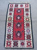 A Turkish Sharkoy Kilim Rug, of geometric design, claret, black and blue central design on a red