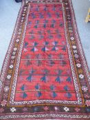 An Afghan Village Rug, with geometric dsign on a claret background with pink and blue arrow shaped