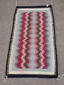 A North American Navajo Indian Blanket/Rug, of geometric design with pink, claret, grey and brown