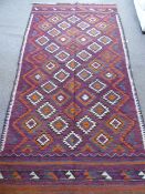 An Afghan Kilim Rug, with geometric design in orange, green, white and grey, approx 265 x 135 cms.