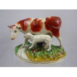 A 19th Century Staffordshire Pottery Cow and Calf Figurine, raised on an oval naturalistic base.