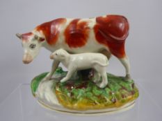 A 19th Century Staffordshire Pottery Cow and Calf Figurine, raised on an oval naturalistic base.