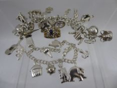 A Lady's Sterling Silver Charm Bracelet, with approx seventeen silver charms on heart shaped clasp