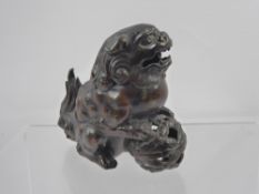 A Bronzed Chinese Guardian Lion (Foo Dog), with paws resting on an embroidered ball, approx 17 x