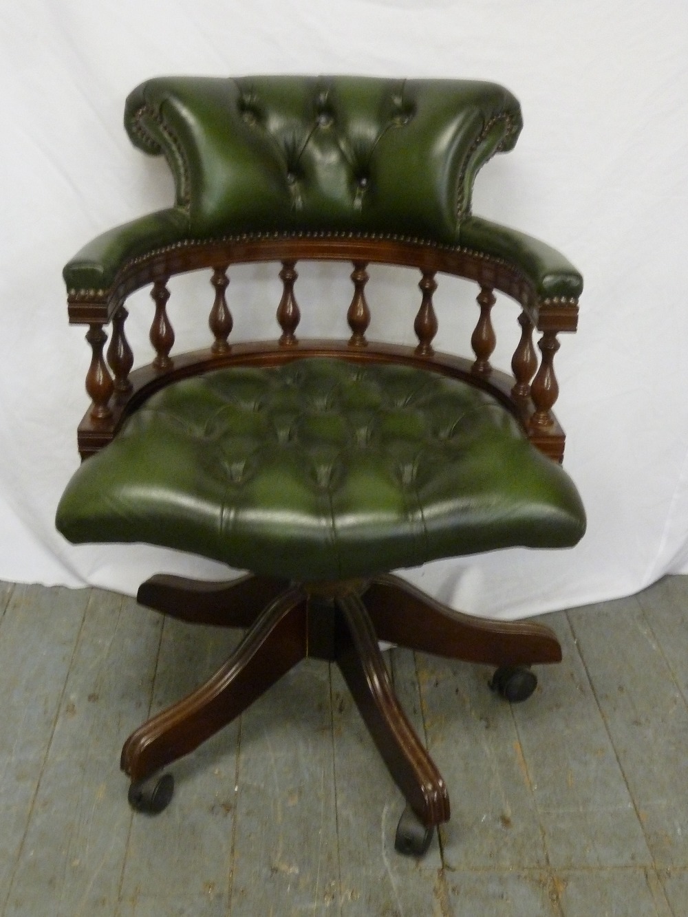 A green leather Captains chair on swivel base