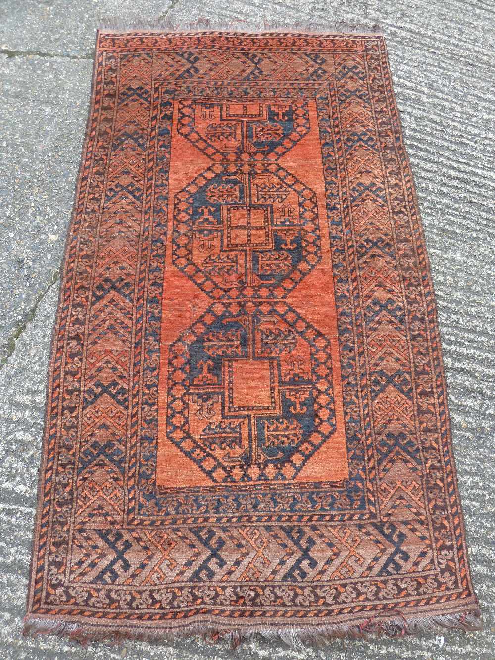 An Oriental wool carpet, orange ground with geometric central medallion within blue and orange