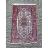 Persian wool carpet, central geometric medallion against a cream ground with blue, brown and red