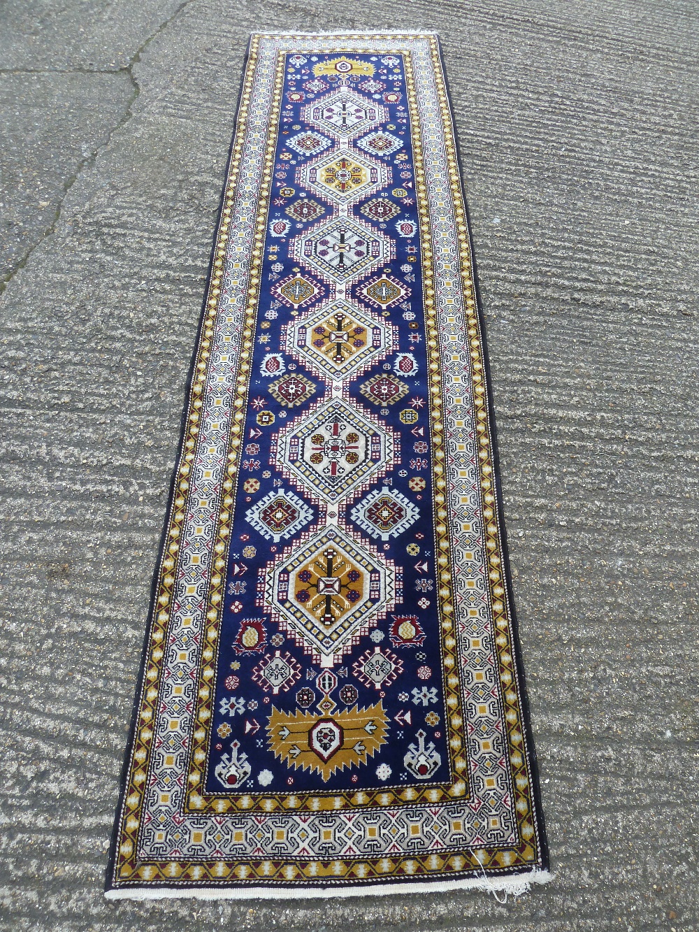 Persian wool runner, geometric repeating patterns against a dark blue ground, 296 x 78cm