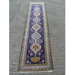 Persian wool runner, geometric repeating patterns against a dark blue ground, 296 x 78cm