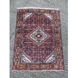 Persian wool carpet, central geometric medallion with red and orange borders, 147 x 109.5cm