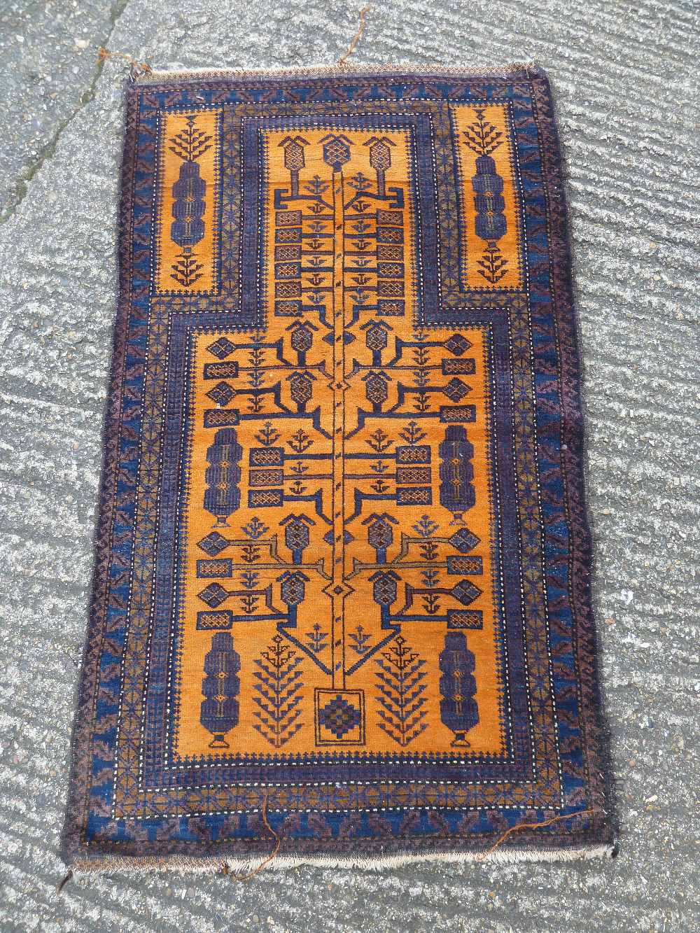 An Oriental wool carpet, geometric symbols against an orange ground within dark blue and brown