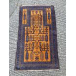 An Oriental wool carpet, geometric symbols against an orange ground within dark blue and brown
