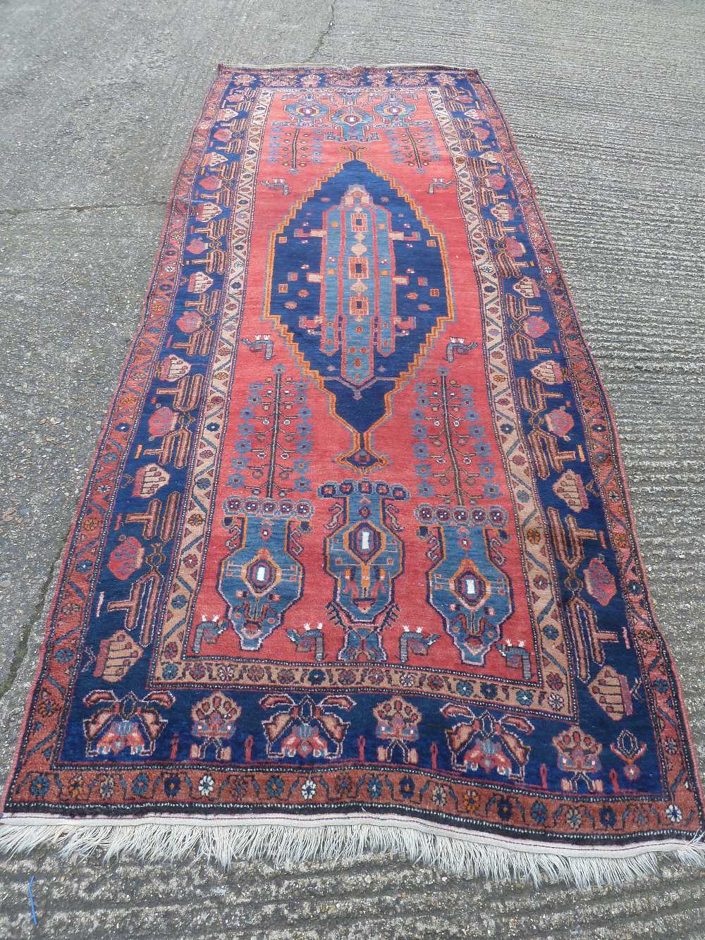 Persian wool carpet, geometric medallions in light and dark blue against a red ground within a