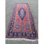 Persian wool carpet, geometric medallions in light and dark blue against a red ground within a