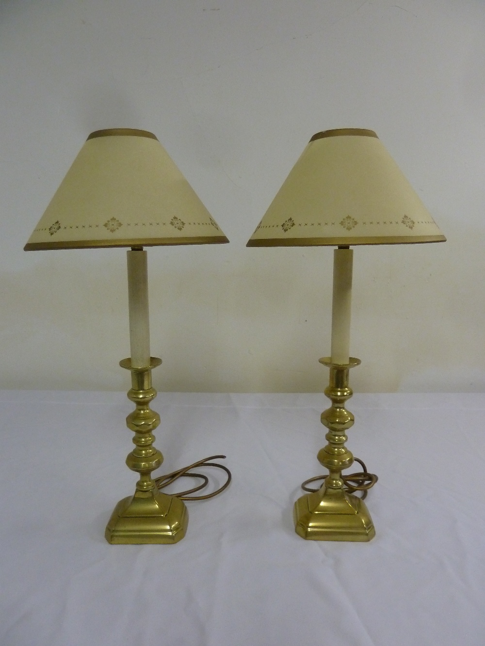 Pair of antique brass candlesticks converted into table lamps, to include shades