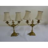 A pair of Victorian gilt metal two branch candelabra on circular bases with silk shades