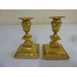 A pair of ormolu dwarf candlesticks of neo-classical form on raised square bases