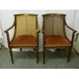 A pair of early 20th century mahogany and bergere armchairs with upholstered seats on fluted