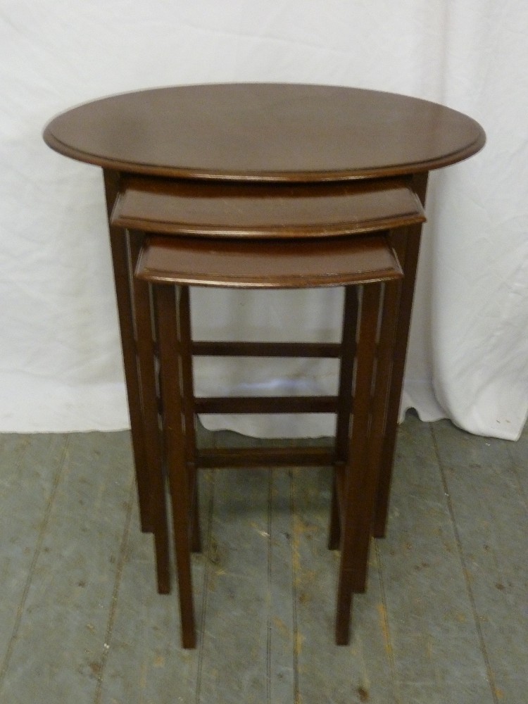 A mahogany oval nest of three tables on four tapering rectangular legs
