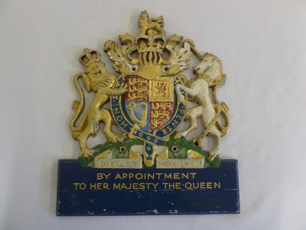 A cast iron gilded and painted QEII coat of arms wall plaque, By Appointment To Her Majesty The