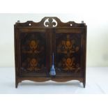 A mahogany rectangular wall hanging cabinet, the hinged doors inlaid with flowers and leaves