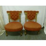 A pair of upholstered gilded boudoir chairs on four carved cylindrical legs