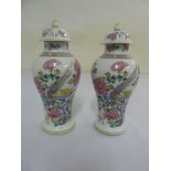 A pair of porcelain vases in the Chinese style with domed pull off covers