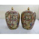 A pair of Chinese famile rose ovoid vases and covers profusely decorated with figures