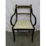 An Edwardian ebonised armchair with upholstered seat on four sabre legs