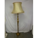 A gilded metal standard lamp on raised circular base with silk shade