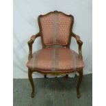 A mahogany upholstered armchair on four cabriole legs