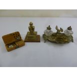 A brass ink stand with two glass inkwells, a decorative brass paperweight and a cased set of balance