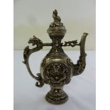 A Tibetan white metal teapot decorated with stylised dragon and with a dragon scroll side handle