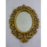 An oval gilt wall mirror pierced and carved with leaves and scrolls