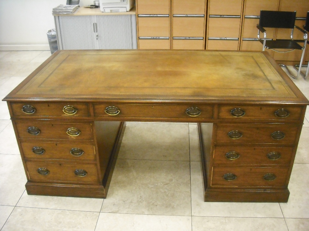 A mahogany reproduction partners desk with tooled leather top, the drawers with brass swing handles