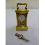 A miniature brass carriage clock with aesthetic movement panels and swing handle to include key