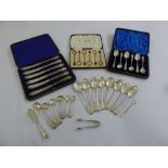 A quantity of silver flatware to include cased butter knives, spoons and a pair of tongs