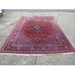 A Kashan style wool carpet red ground with repeating floral and swag patterns, 336 x 244 cm