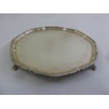 A circular silver salver with gadrooned border on four scroll feet, Sheffield 1917