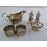 A quantity of silver to include a sauce boat, a condiment set and two napkin rings