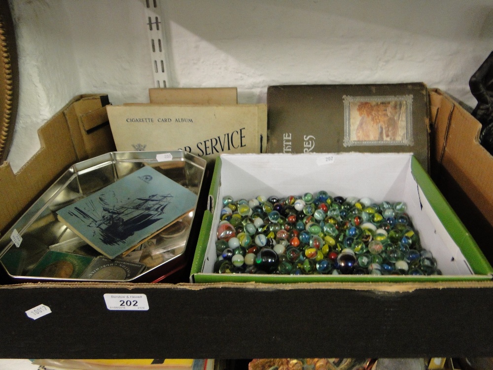 Box containing cigarette cards, marbles and coins.
